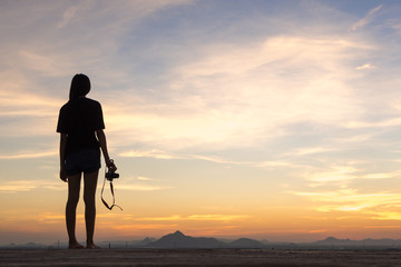 Girl photographer with camera at sunset