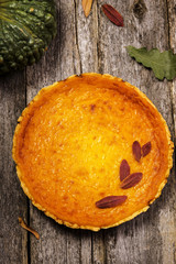 Pumpkin pie on the shabby wooden background with pumpkin, chestnuts and autumn leaves. Selective focus 