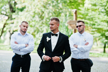 Personable groom with best mans or groomsman posed on park at we