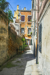 Narrow canal among old colorful brick houses in Venice