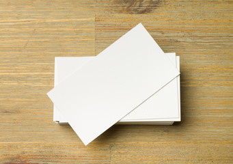 Stack of white not aligned business cards on a brown wooden table