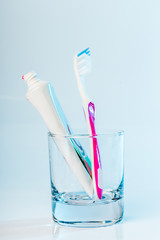 Toothbrushes in glass on table on light background