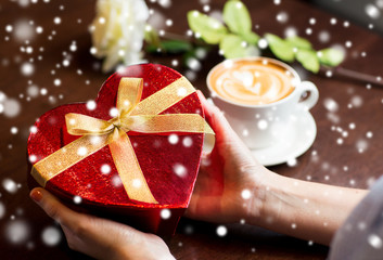 close up of hands holding heart shaped gift box