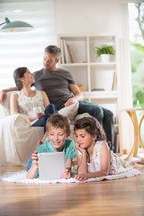 Cheerful family at home. two kids playing with a digital tablet