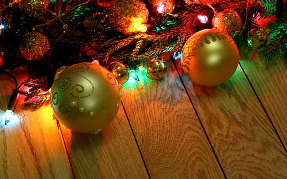 New Year`s top corners border  from Christmas tree fir branches, golden pine cones, balls, garland lights on vertical old wooden desk table background. Big copyspace for holiday congratulations.
