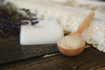 Salt and soap with herbs on wooden background