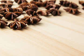 Anise star close up on wooden beige background. Decorative border of star anise spice on wood board.