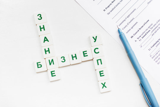 Russian scrabble words on business concept with pen and contract paper. Featured words are: Knowledge, Business, Success. Isolated with free space
