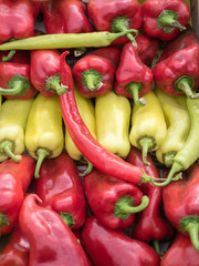 Background of a stacked colourful peppers on sale at the market. Yellow and red peppers pattern close up.
