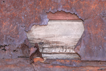 old rusty metal sheet beaten on wooden background 