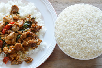 spicy stir fried chicken with basil leaf on rice and paddy in bowl