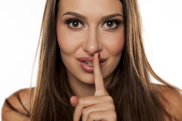 Fototapeta premium young woman with a finger to her lips. concept for silence