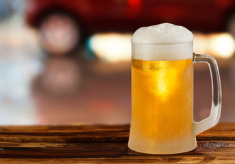 cold glass mug of beer with foam on the background of the street
