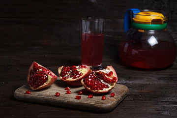 pomegranate juice with sliced pomegranate on a wooden board.