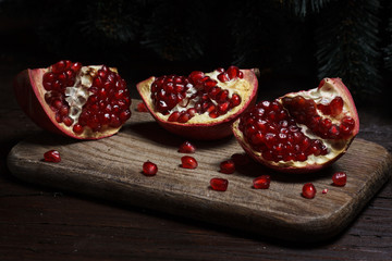 cut part of pomegranate on a wooden board on a wooden background on the background of trees. New Year's holiday. tree branch