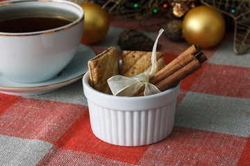 Cinnamon sticks on a table. Feast of the new year, Christmas tree in the background, toys