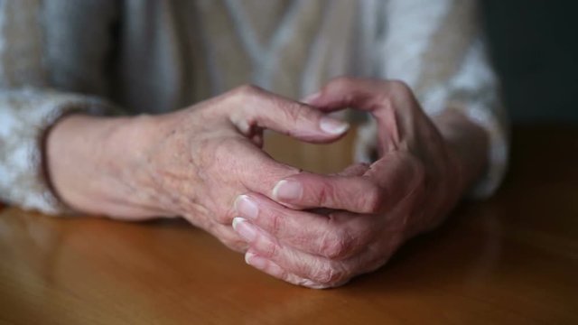 closeup of old woman’s hands on table moving nervously
