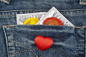 Rea heart and colored condom in blue jeans pocket