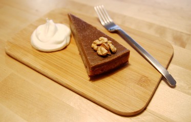 Cake, cream and fork on wooden board