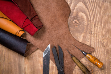 Set of leather craft tools on wooden background. Workplace for shoemaker.