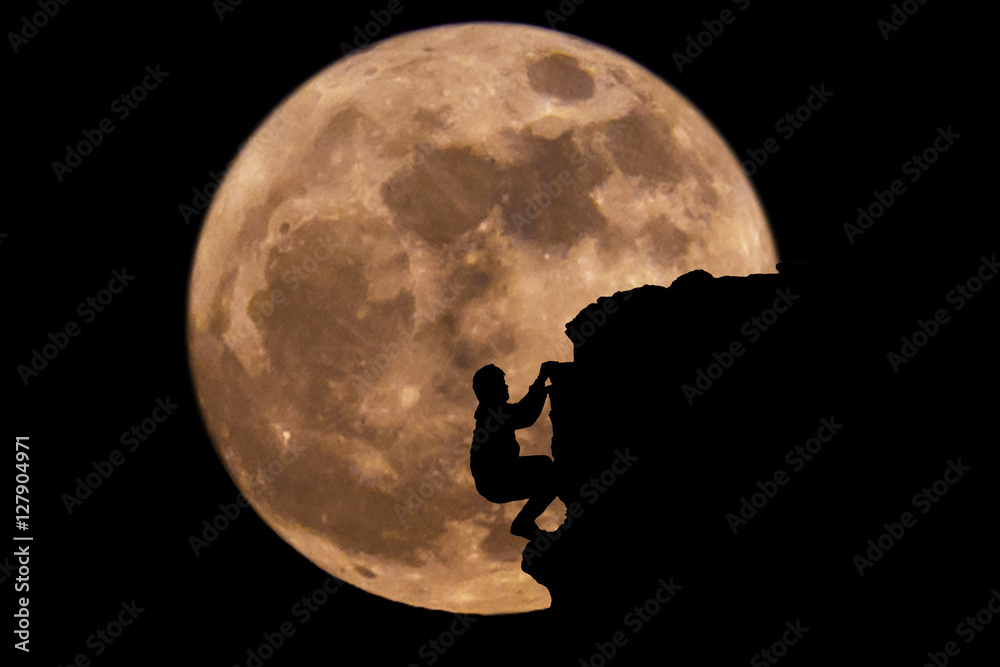 Wall mural silhouette man climbing on a cliff with full moon