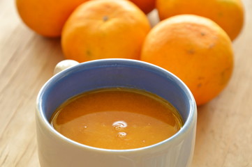 orange juice in cup and tangerine on wooden table