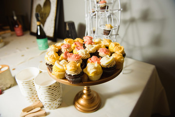 Cupcakes with pink and yellow cream stand on bronze dish