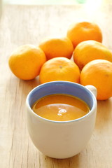 orange squeeze in cup and tangerine on wooden board