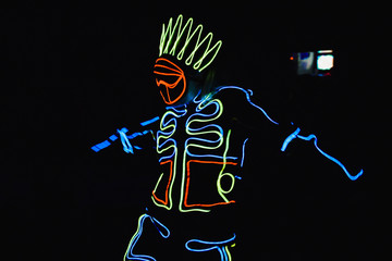 Man in costume of the Indian with light lines dances in the dark