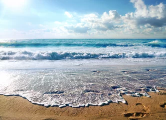 Foto op Plexiglas Oceaan golf Beautiful waves ocean or sea in the summer bright blue, azure and turquoise colors in the early morning in sun light. Sea foam, yellow sand of beach at the resort. Beautiful sky with white clouds.