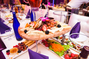 Cut fruits and cheese served on wooden plate