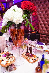 White and red bouquets stand on high vases on dinner table