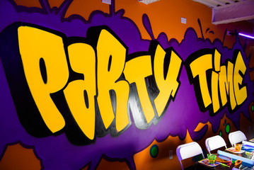 Yellow lettering 'Party time' written on the wall