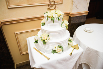 White cake decorated with roses stands on little table
