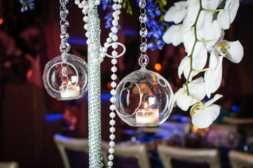 Balls with candles hang from  the lamp with white orchids