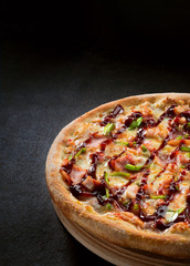 Fresh pizza with BBQ sauce on wooden cutting board