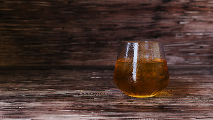 glass of whiskey with ice on rustic wooden table