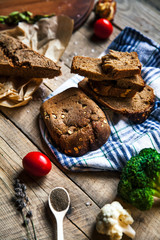 A loaf of fresh rustic wholemeal rye bread on a wooden board, rural food background.