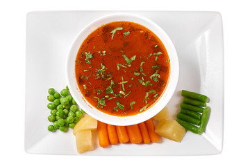 Traditional Romanian vegetables soup chorba with tomatoes sauce (Ciorba de legume). On white plate...