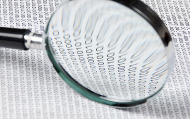 magnifying glass on a binary code