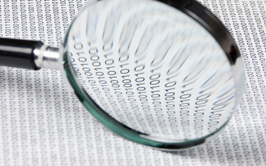 magnifying glass on a binary code