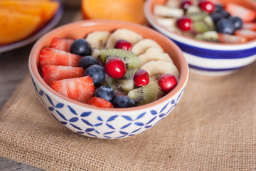 Smoothie  with fruits and berries on the grey wooden table, with variety of fruits around, selective focus