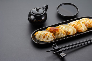 A plate of Japanese gyoza over black background