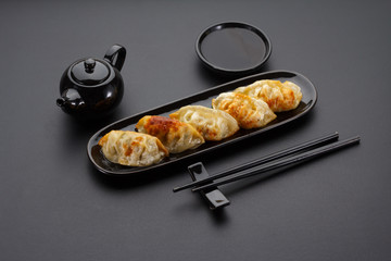 A plate of Japanese gyoza over black background