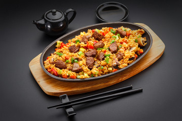 Japanese cuisine. Rice with veal over black background.