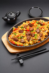 Japanese cuisine. Rice with veal over black background.