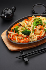 Asia food. Udon noodles with vegetables on a black table