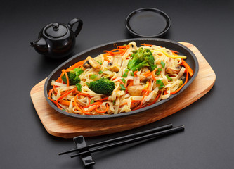 Asia food. Udon noodles with vegetables on a black table