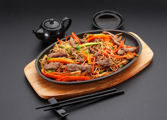 Soba noodles with veal over black background