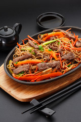 Soba noodles with veal over black background